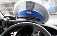 Czapka policjanta ruchu drogowego leży na podszybiu radiowozu oznakowanego